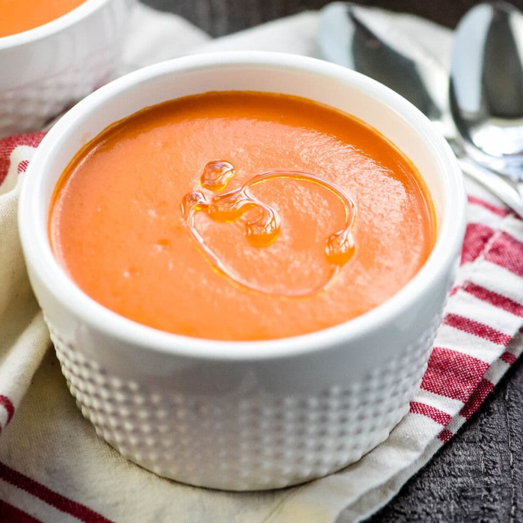 Gazpacho made with cucumber and tomato in bowl with drizzle of olive oil.