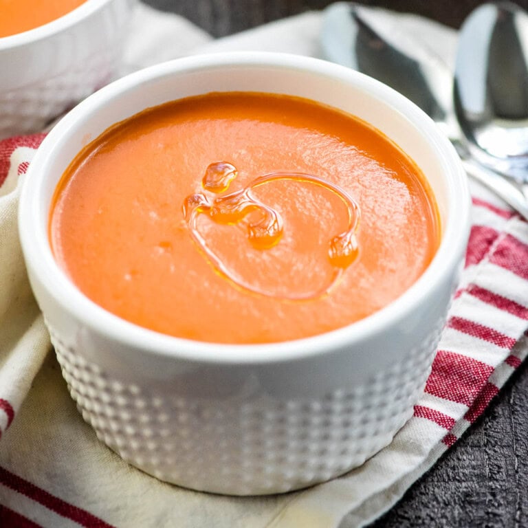 Gazpacho made with cucumber and tomato in bowl with drizzle of olive oil.
