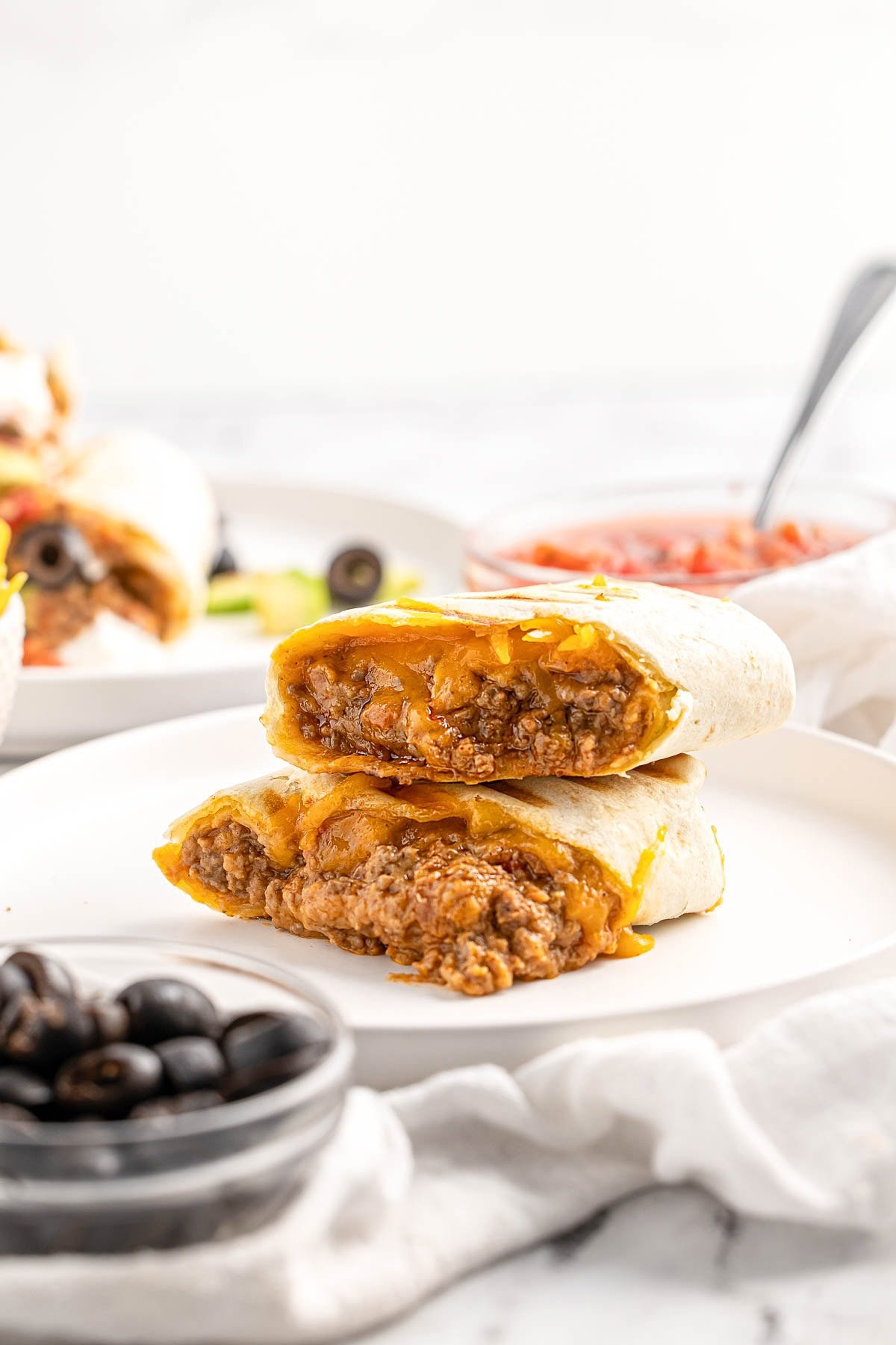 Beef and Bean Burritos recipe stacked on plate.