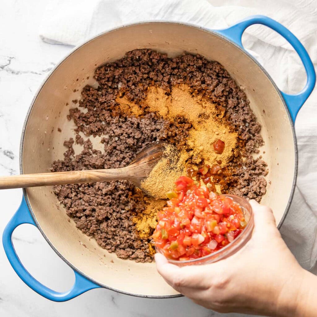 Adding salsa to pot.