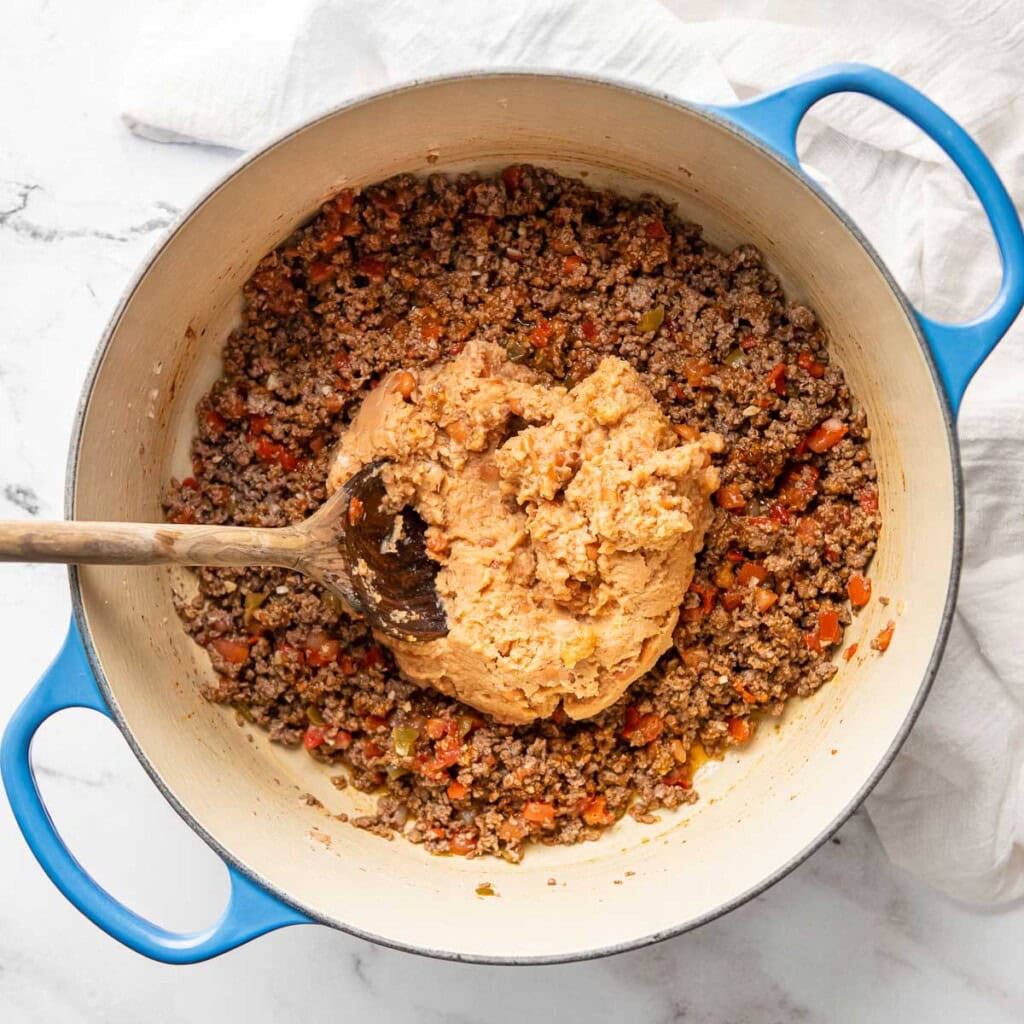 Adding refried beans to Beef and Bean Burritos mixture.