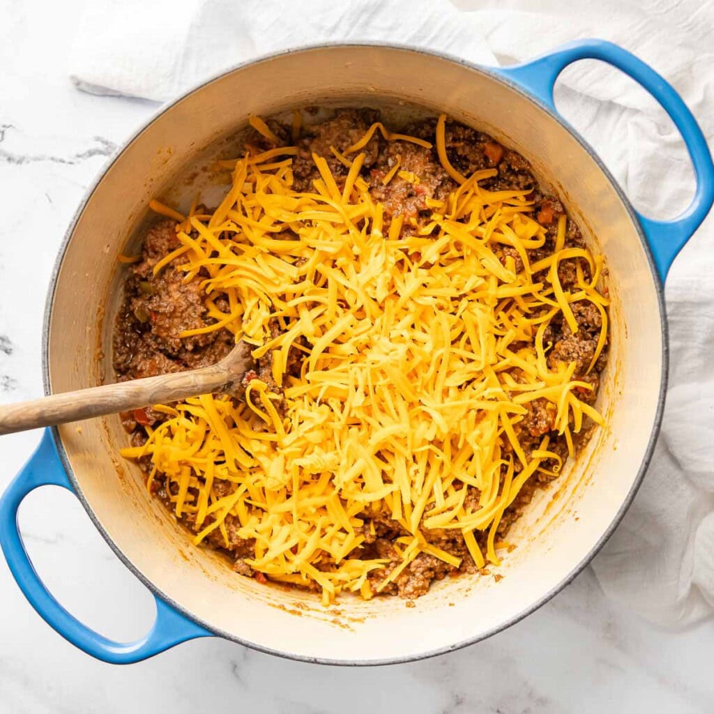 Adding shredded cheese to Beef and Bean Burritos mixture.