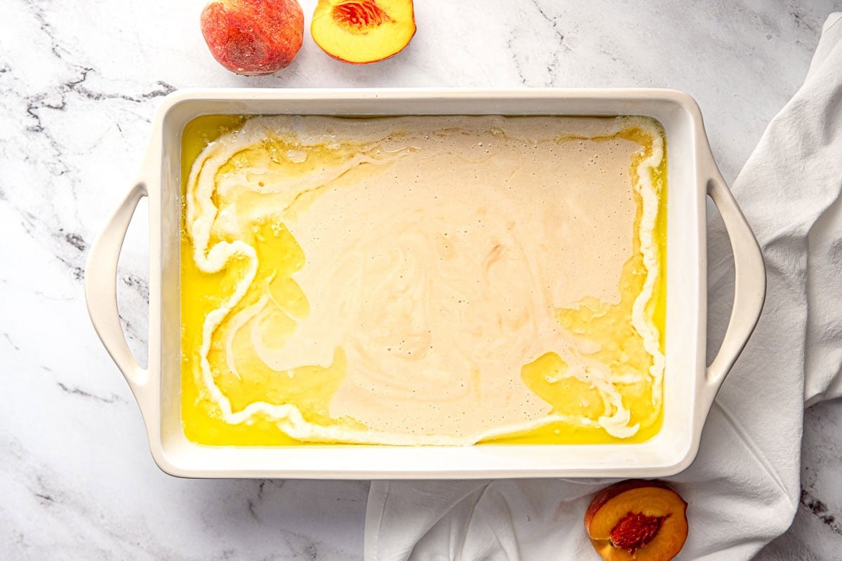 Batter poured into dish of melted butter for Easy Peach Cobbler recipe.