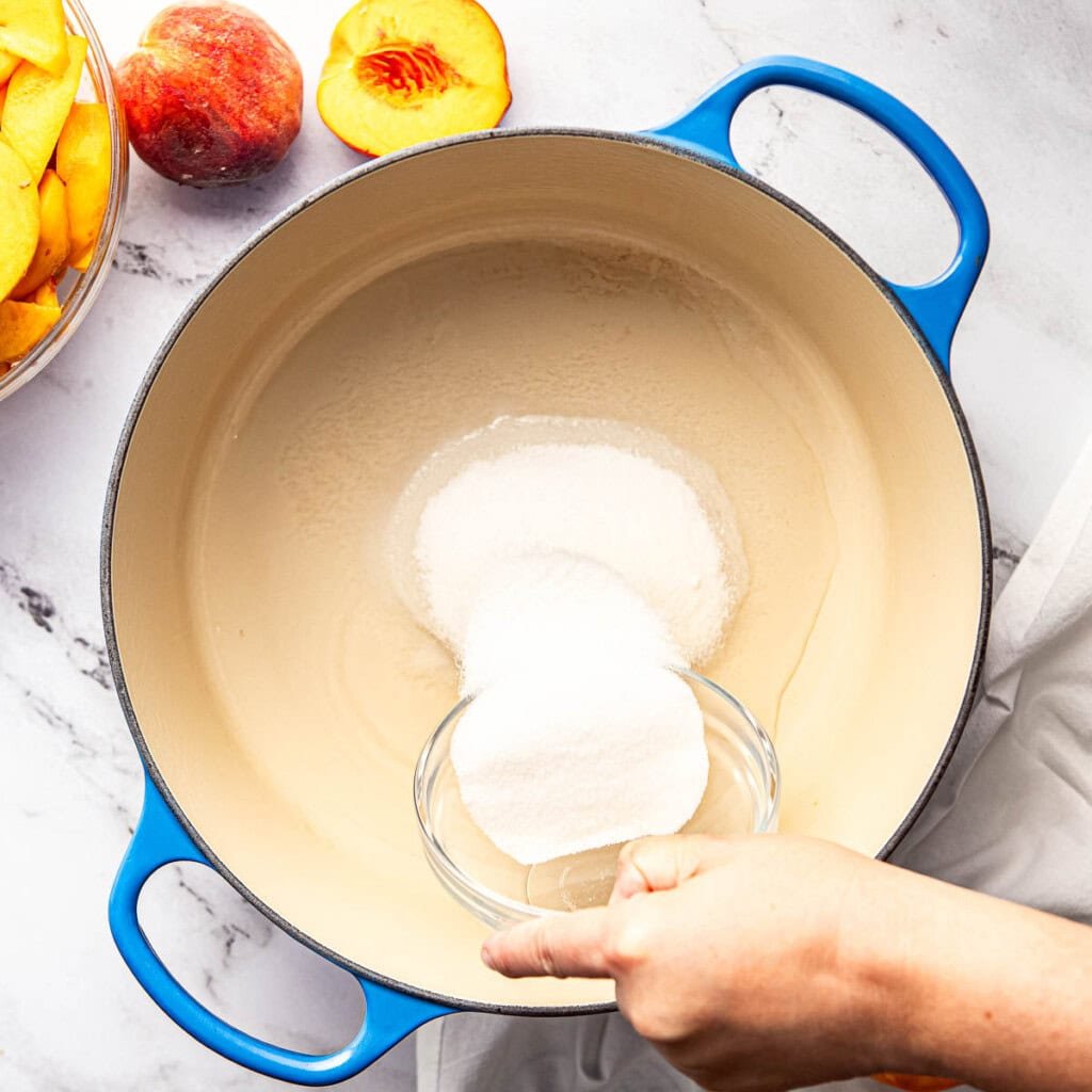 Adding sugar to water in pot.