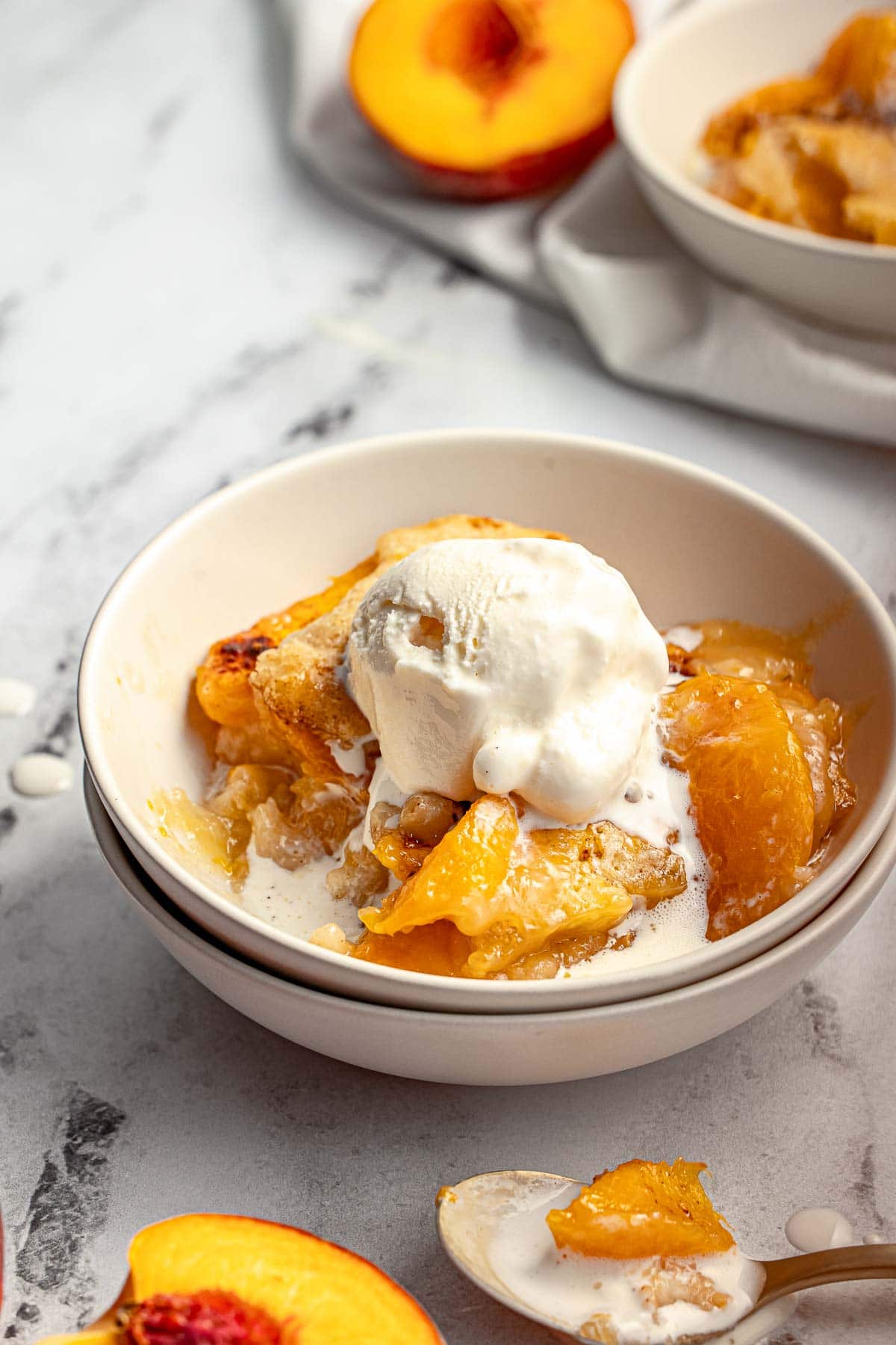 Easy Peach Cobbler with melting ice cream in bowl.