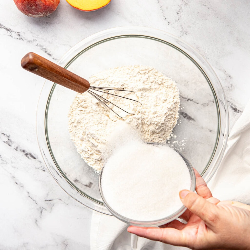 Pouring sugar into flour for Easy Peach Cobbler recipe.