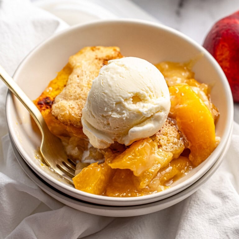 Easy Peach Cobbler with ice cream in bowl with fork.