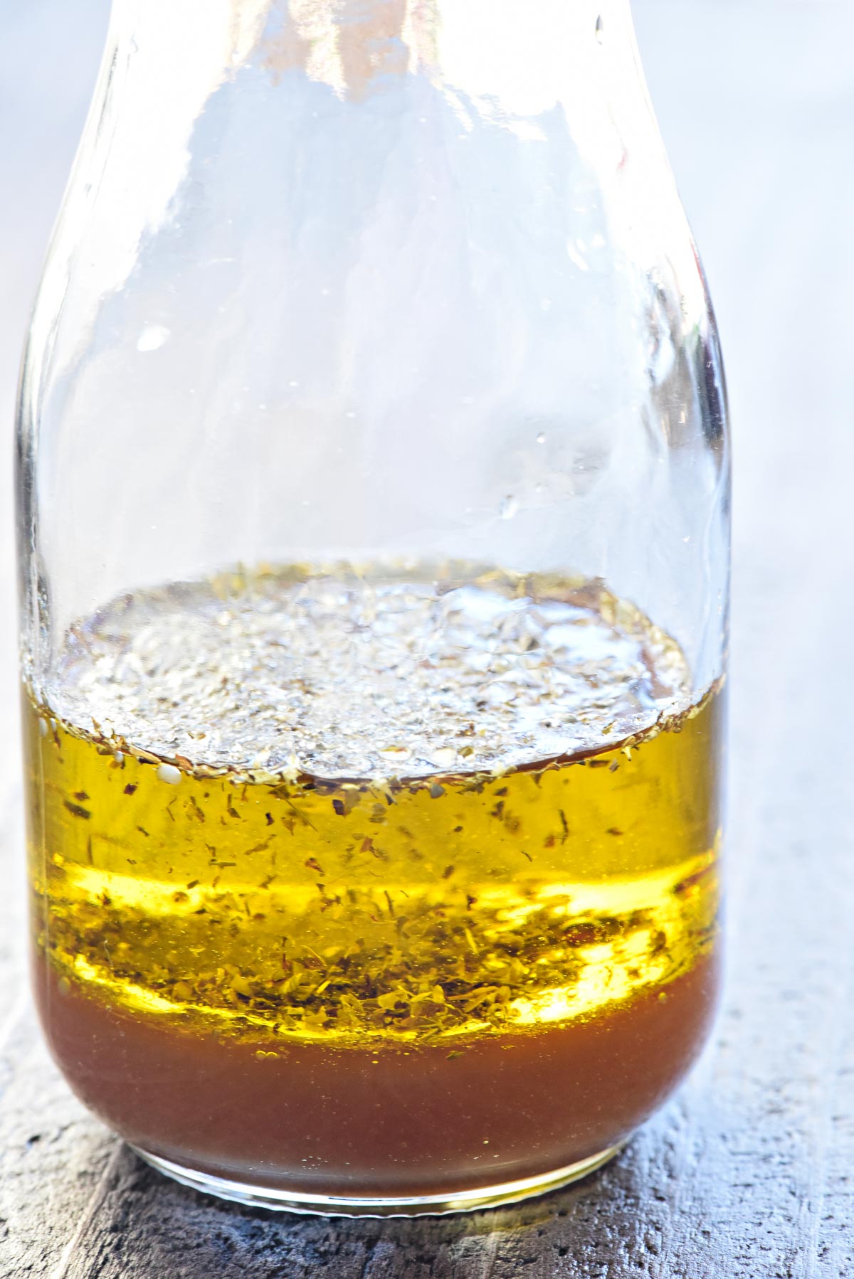 Greek Salad Dressing ingredients layered in glass jar.
