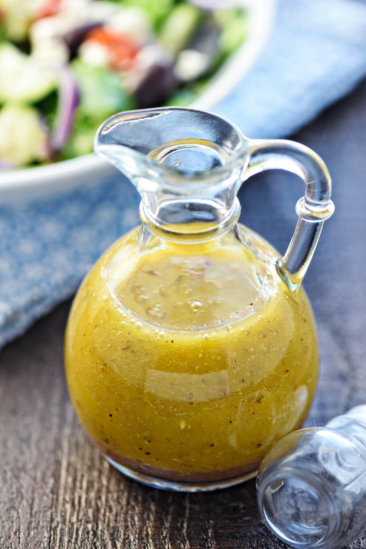 Greek Salad Dressing in bottle with lid on table.