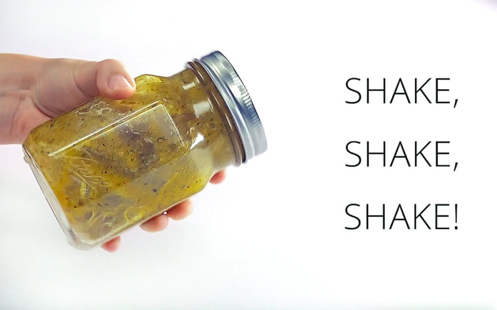Shaking Greek Salad Dressing recipe in jar.
