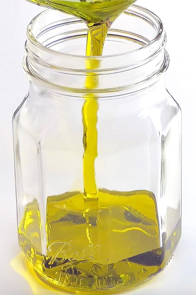 Pouring oil into jar.