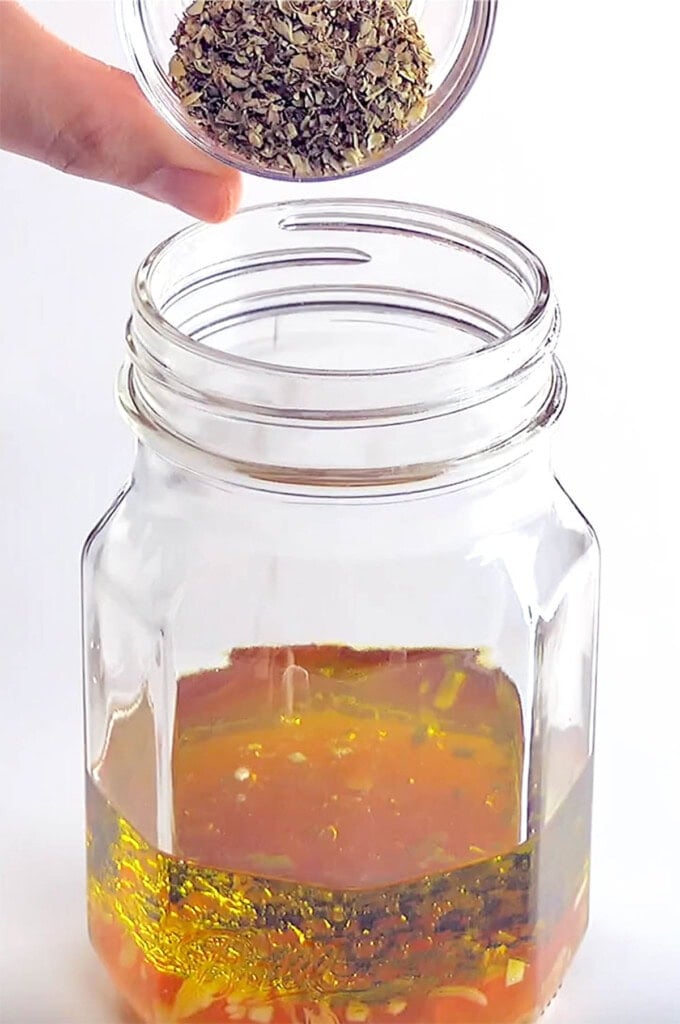 Adding dried herbs to jar.