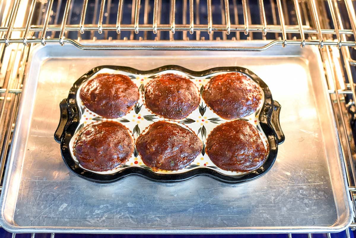 Muffin tin meatloaf on baking sheet in oven.