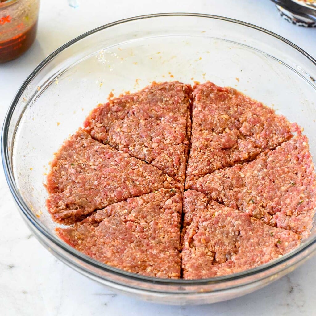 Muffin tin meatloaf mixture divided into sixths in bowl.