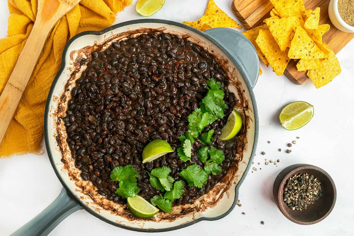 Skillet garnished with cilantro and limes.