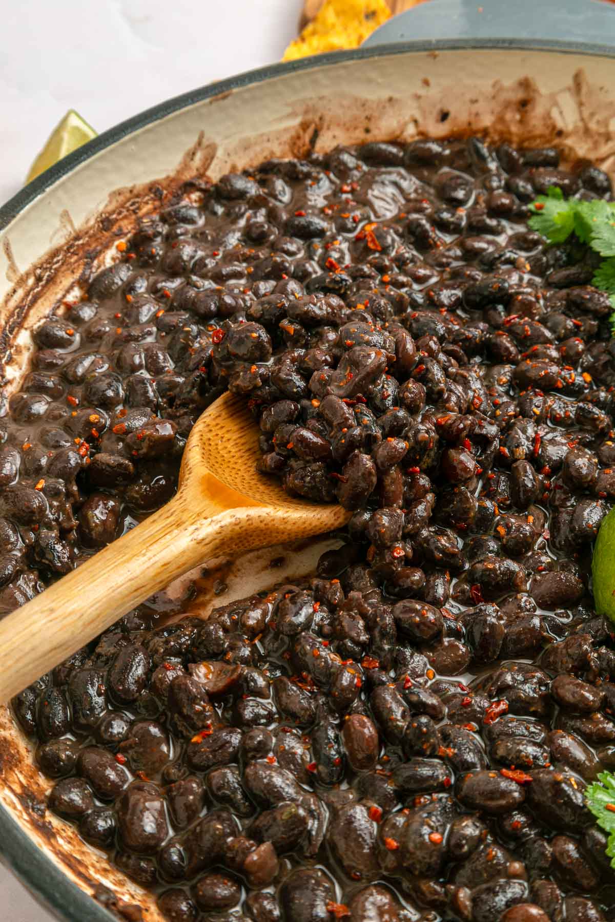 Seasoned Black Beans scooped with wooden spoon.