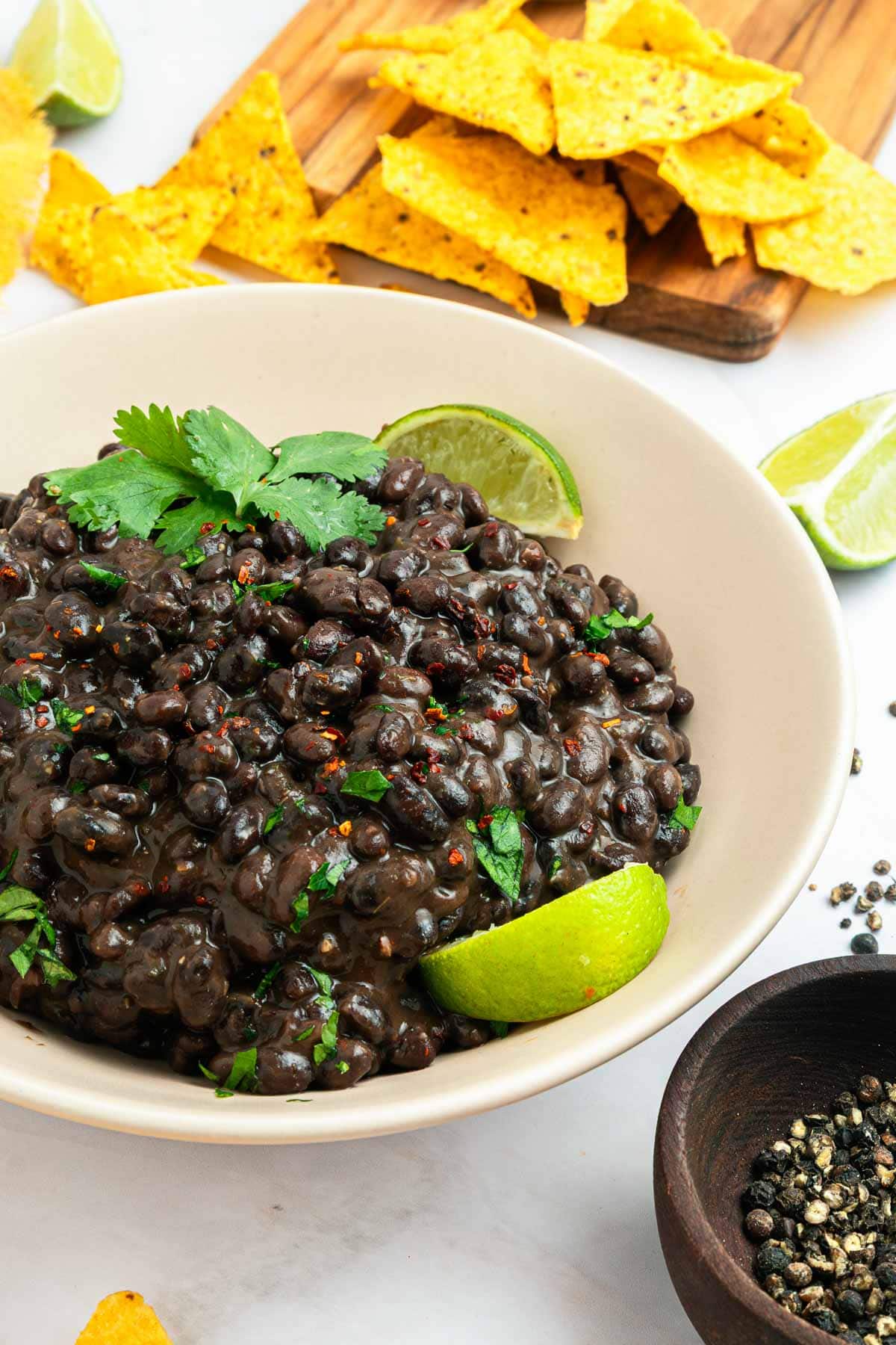 Seasoned Black Beans in bowl with lime wedges.