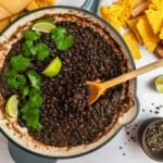 Seasoned Black Beans aerial view in pan with serving spoon and garnishes.