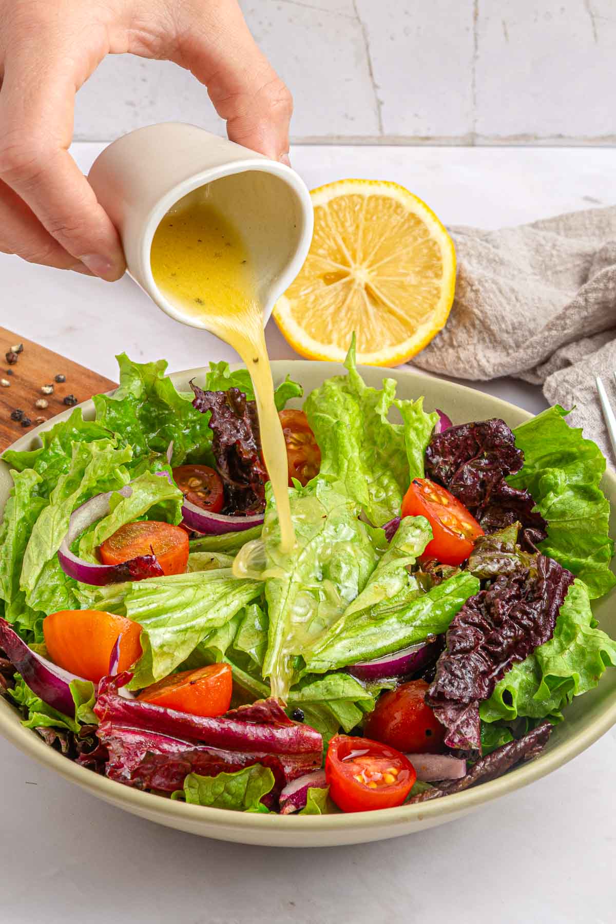 Pouring white balsamic dressing over salad.