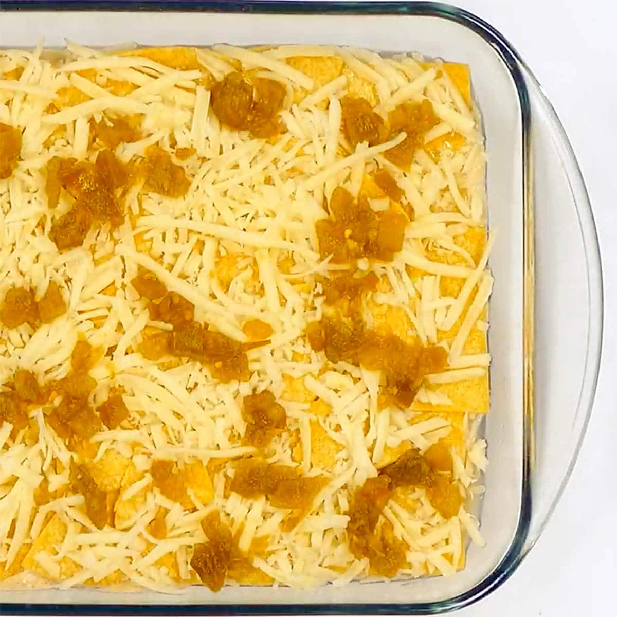 Sprinkling green chiles over easy Chicken Enchilada Casserole.