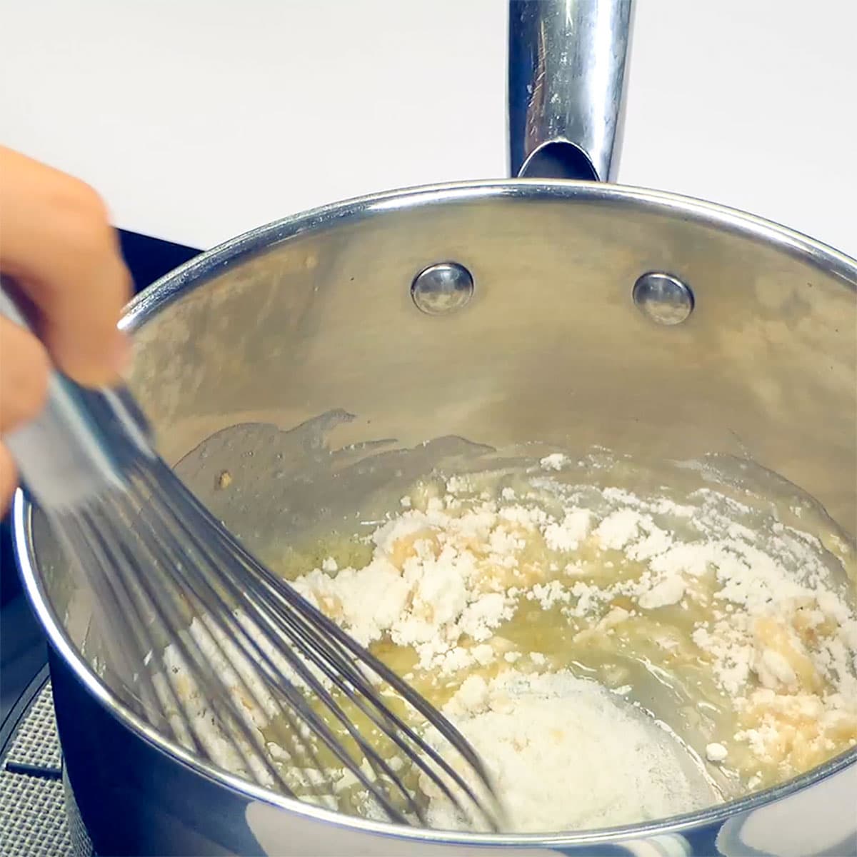 Whisking flour into melted butter.