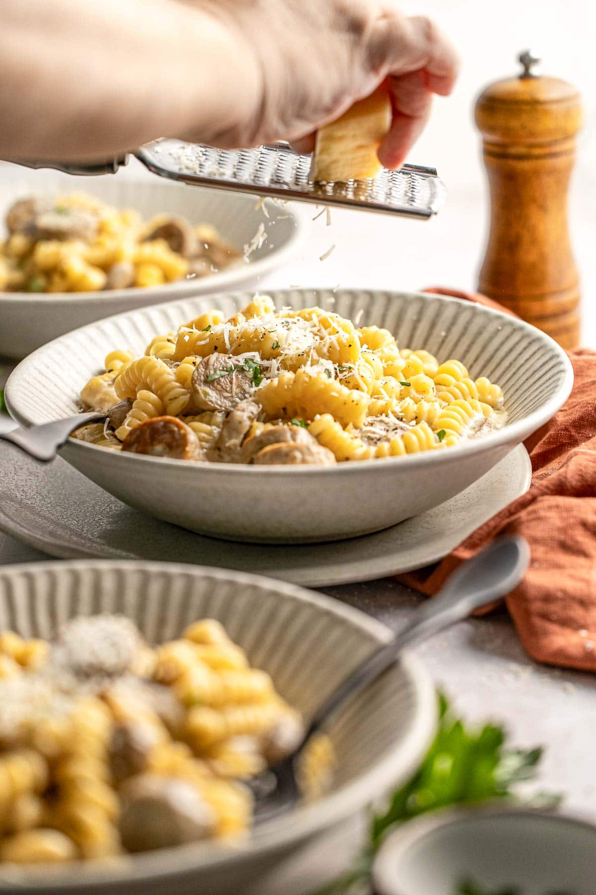 Chicken Sausage Pasta being sprinkled with fresh Parmesan.