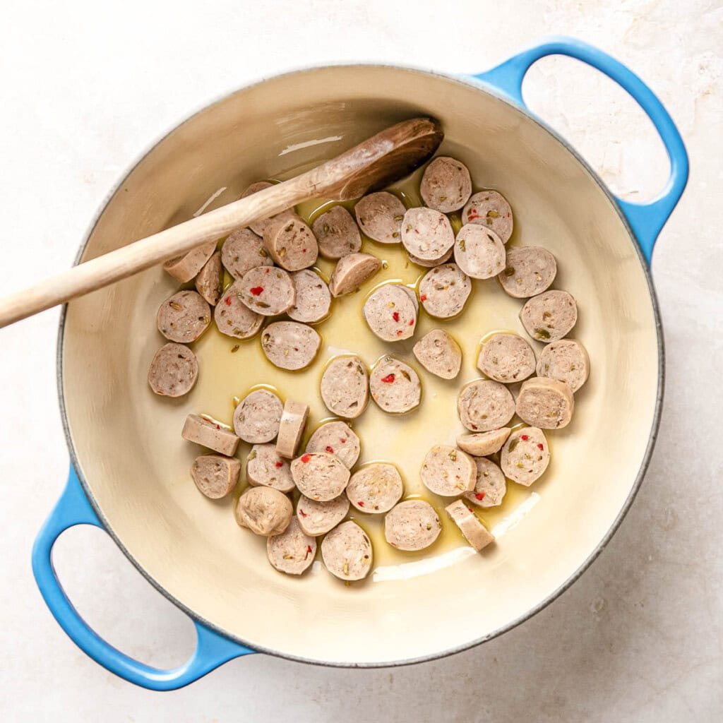 Sauteing sausage in pot.