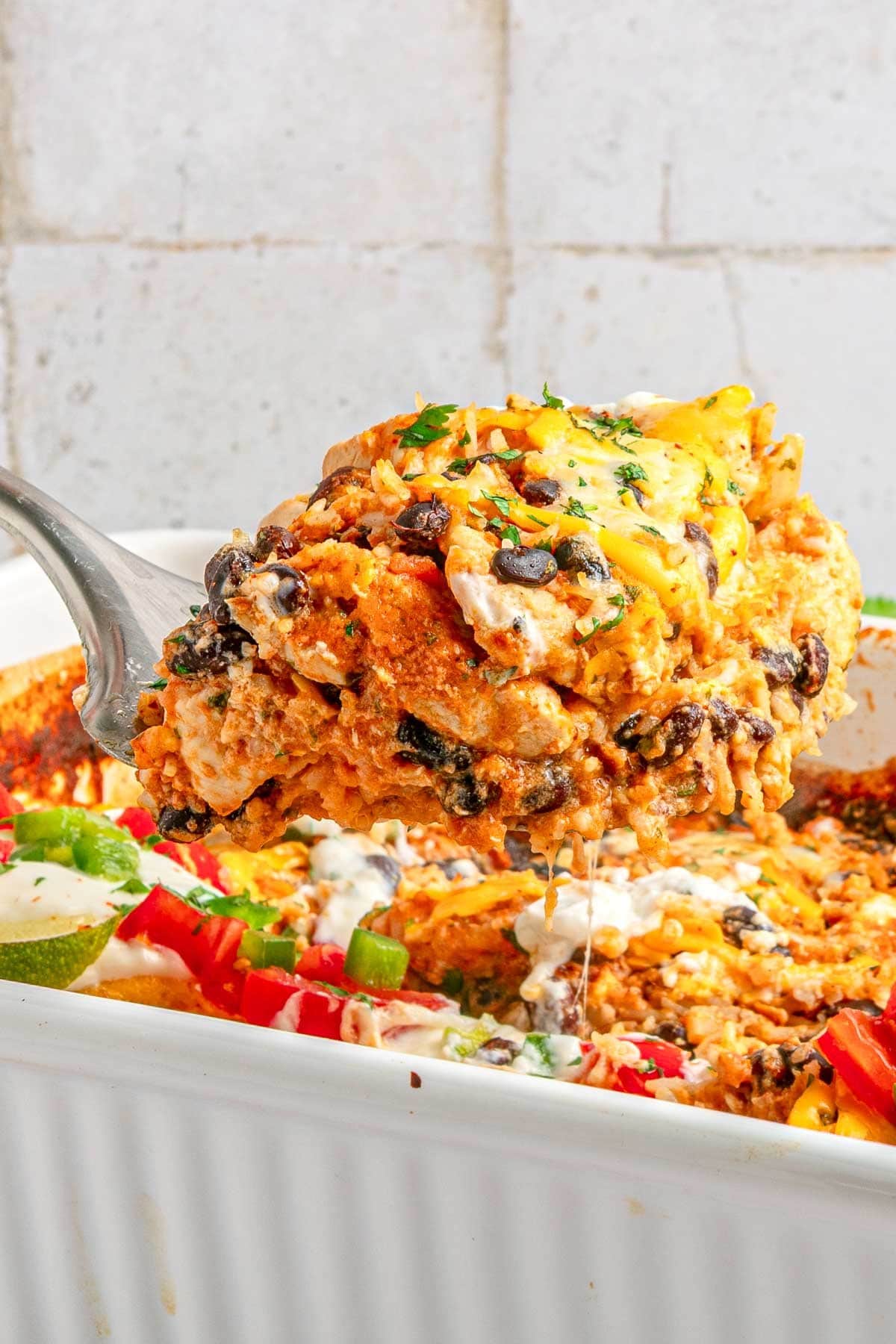 Mexican Chicken and Rice Casserole on metal spatula over baking dish.