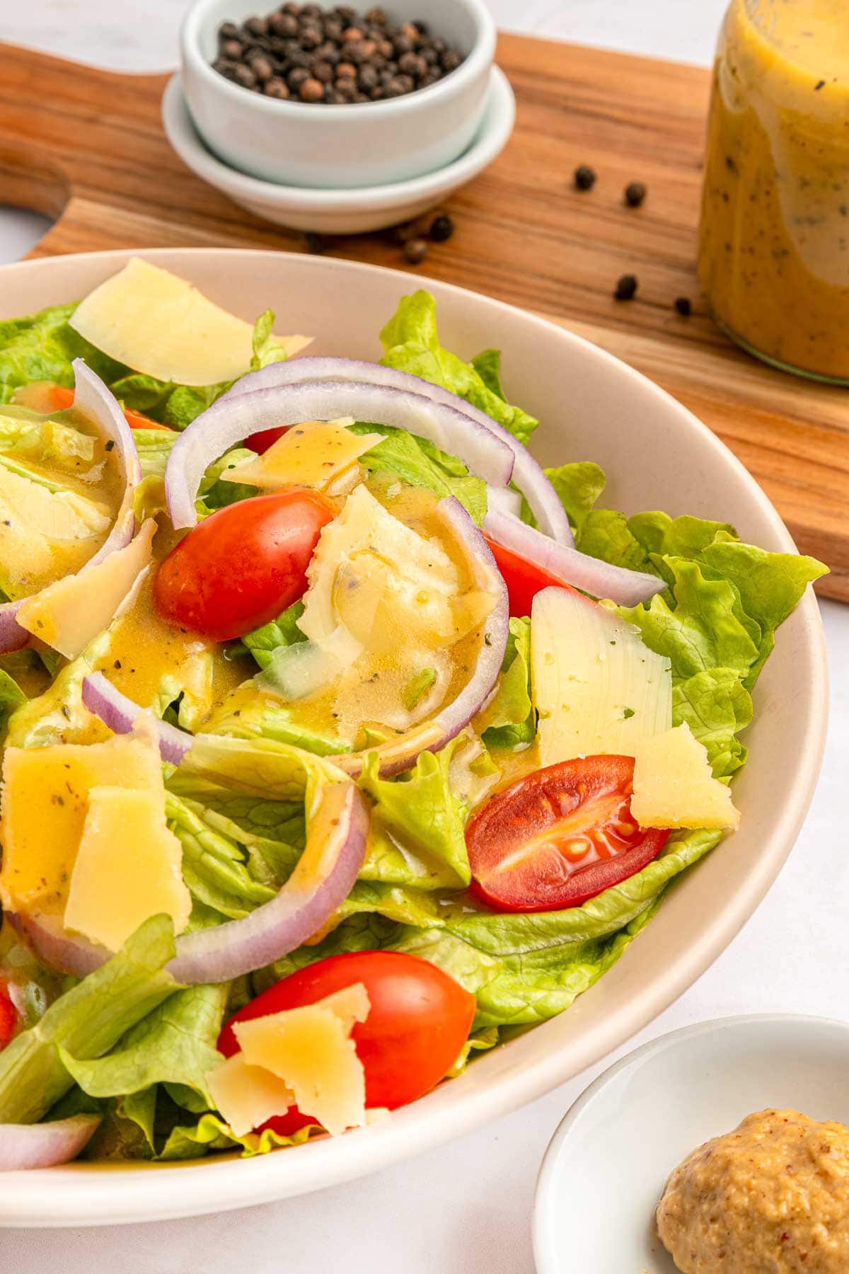 Red Wine Vinaigrette close-up over salad of lettuce, tomatoes, onions, and Parmesan.