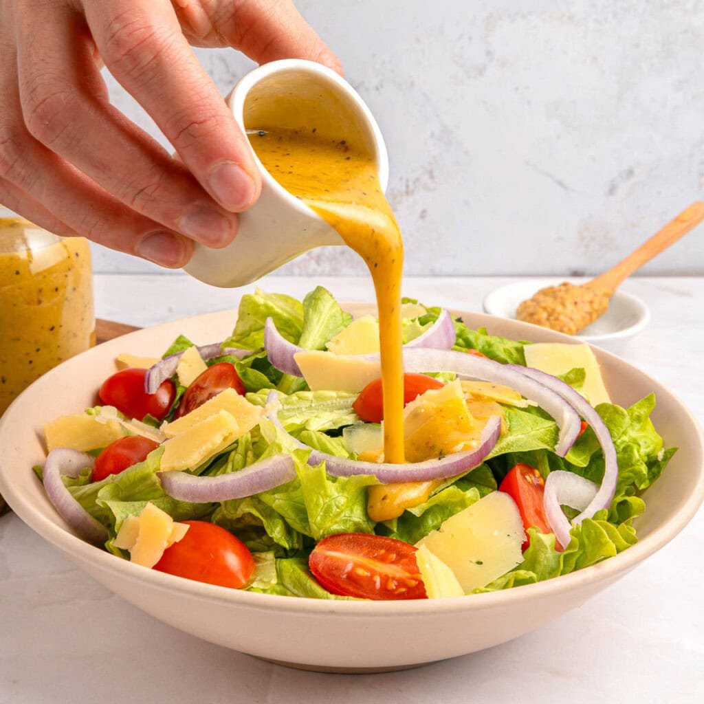 Red Wine Vinaigrette being poured over colorful salad.