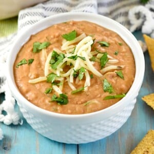 Bean Dip recipe in white bowl with garnishes.