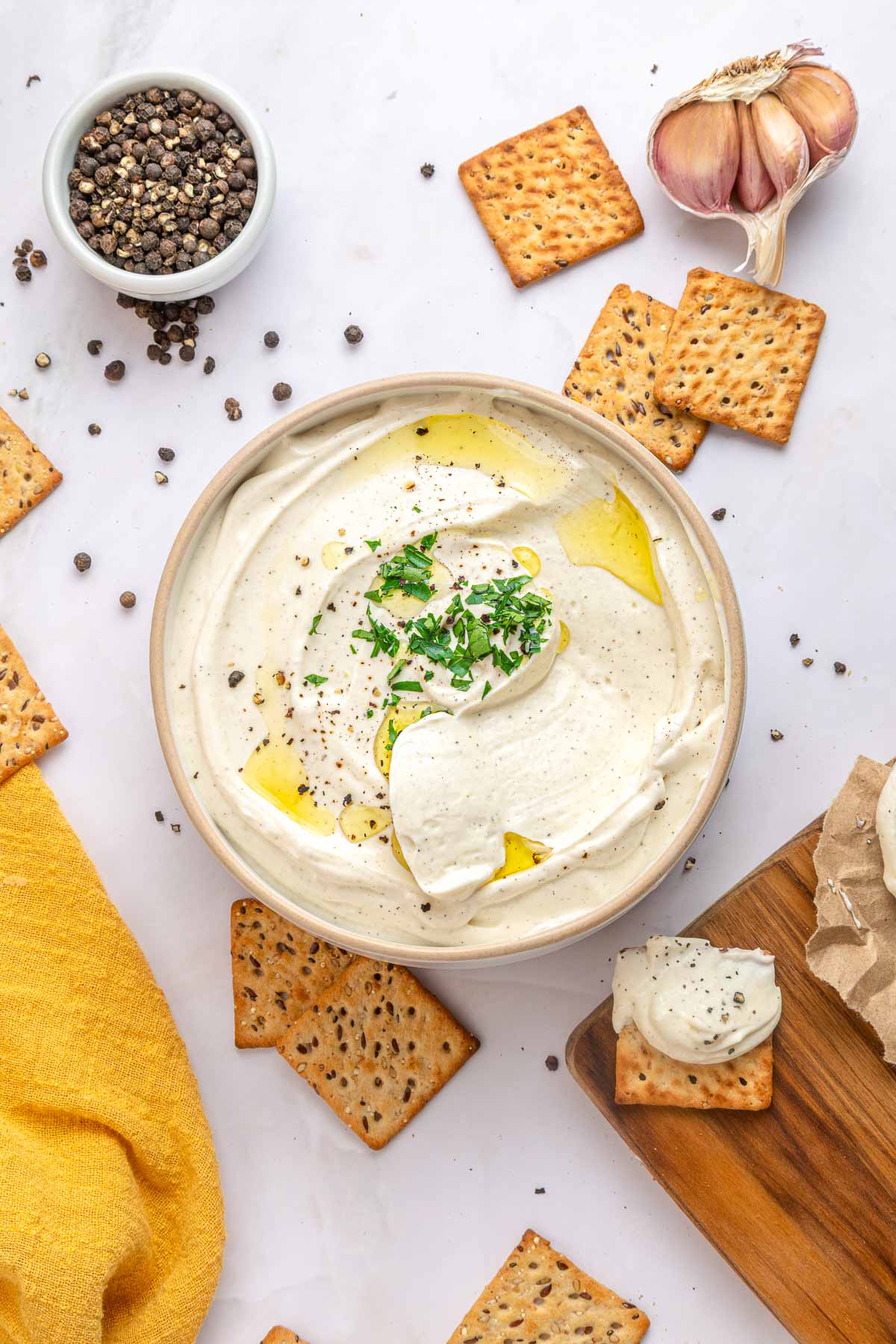 Cream Cheese Dip aerial view with crackers, garlic, and peppercorns.