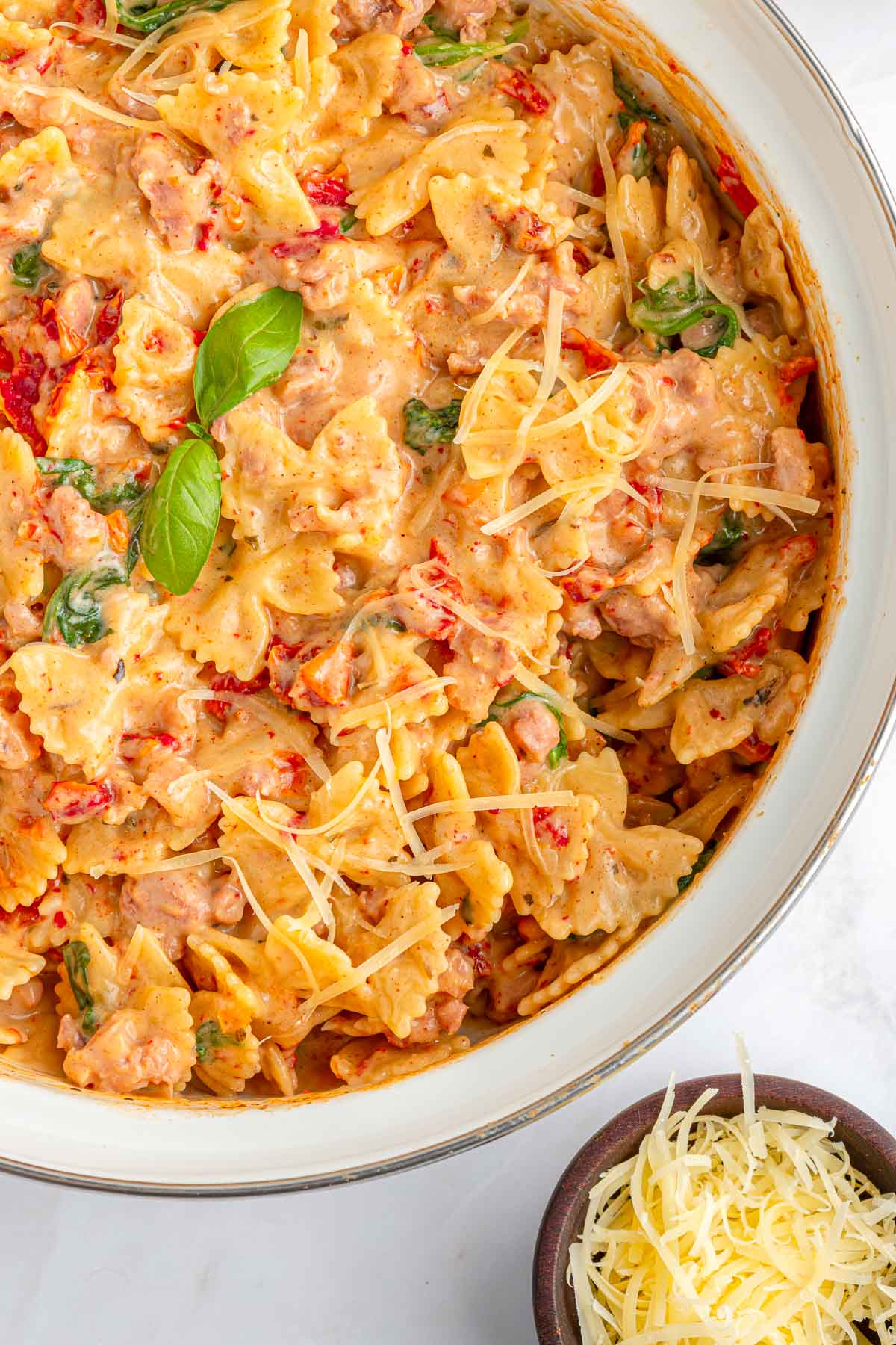 Creamy Sausage Pasta garnished with basil and Parmesan.