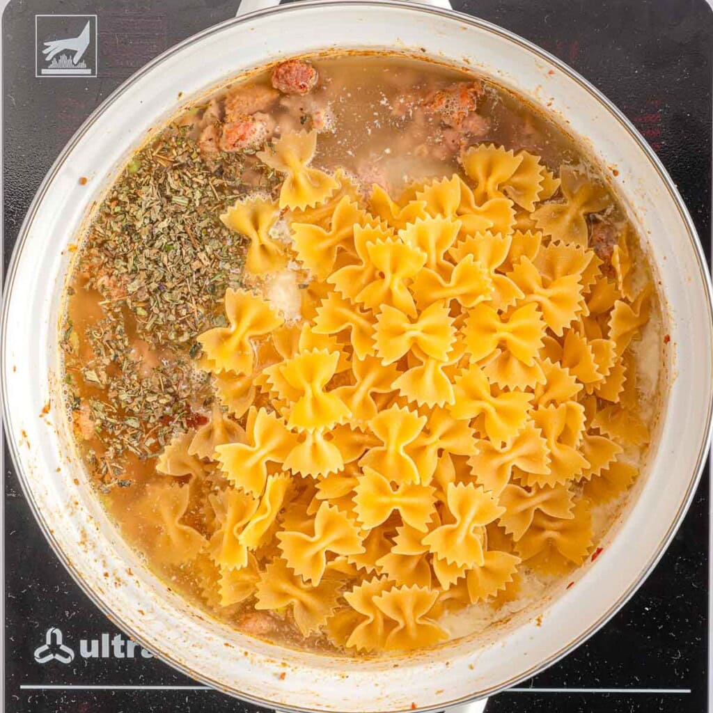 Adding farfalle to Creamy Sausage Pasta.