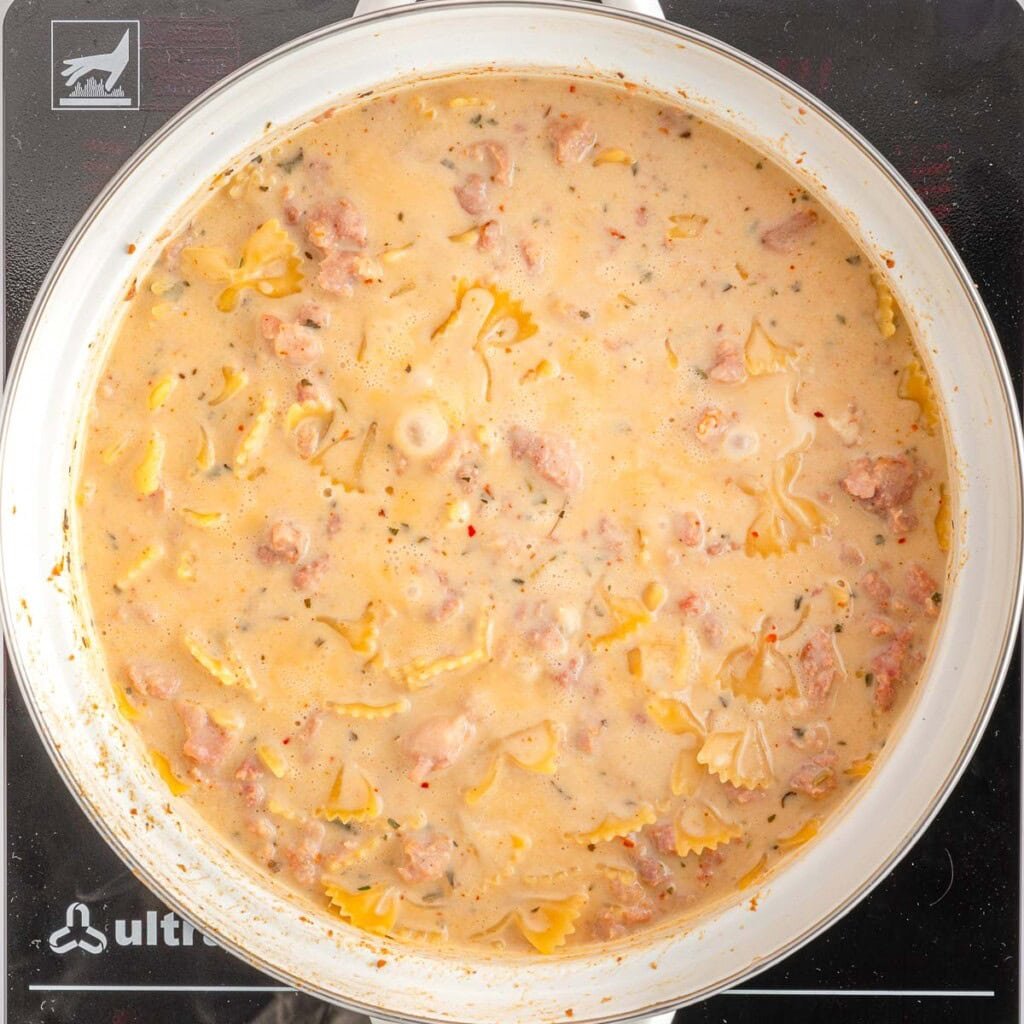Creamy Sausage Pasta simmering in pot.