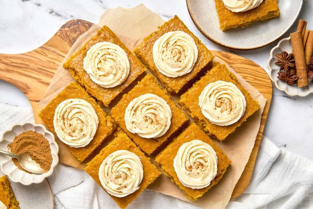 Pumpkin Bars with Cream Cheese Frosting on wooden board.