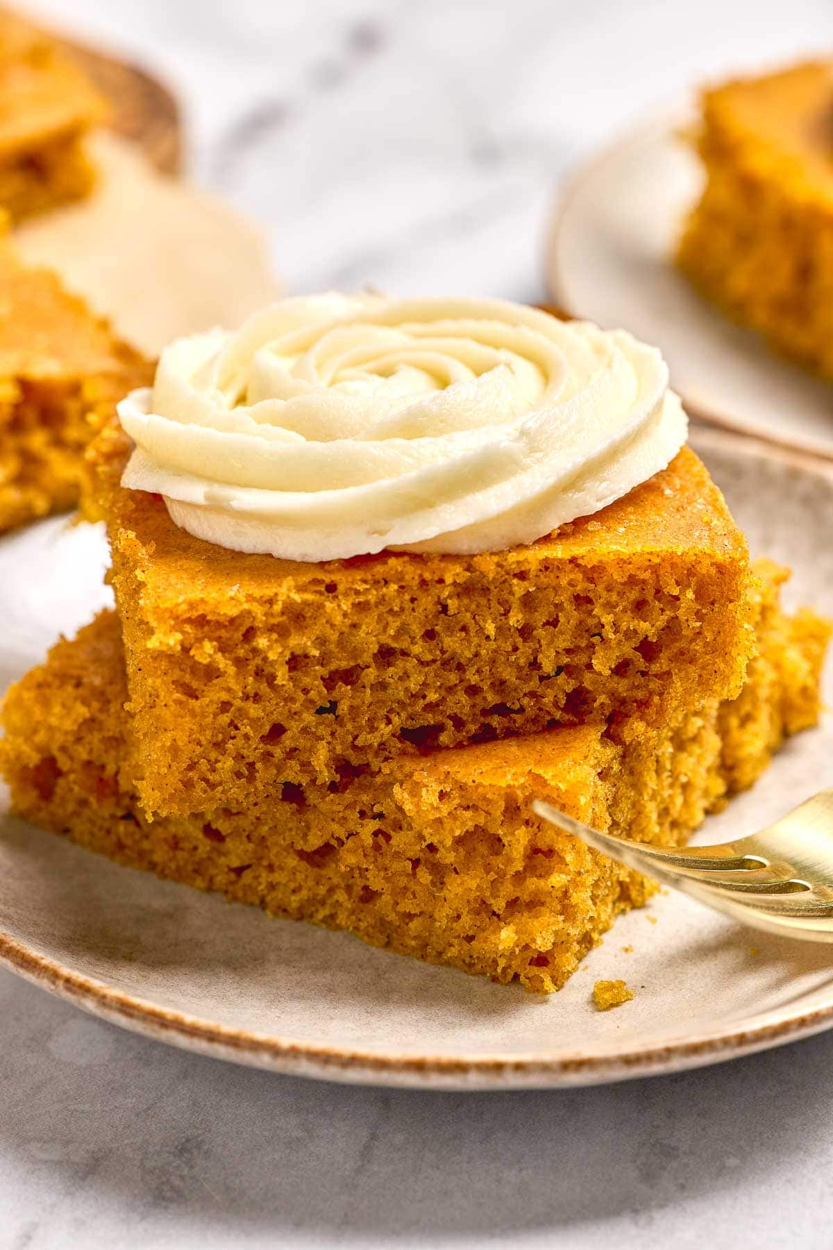 Pumpkin Bars with Cream Cheese Frosting stacked on plate.