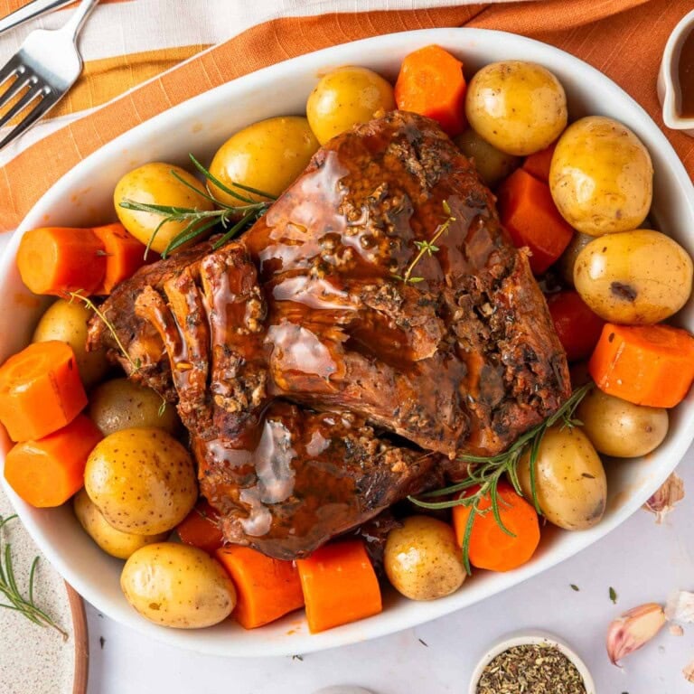 Slow Cooker Pot Roast on platter with potatoes, carrots, and herbs.