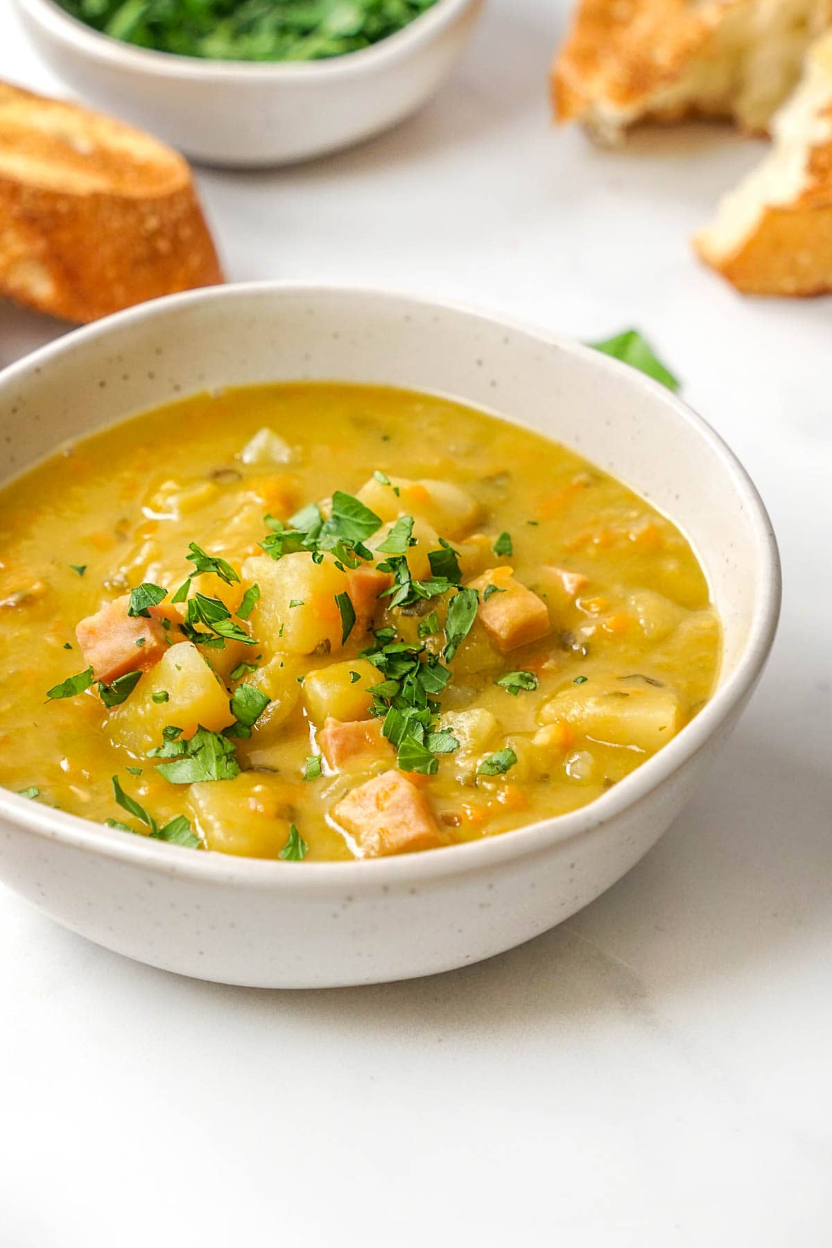 Slow Cooker Split Pea Soup on table with bread and parsley.