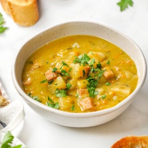 Slow Cooker Split Pea Soup in bowl with ham, potatoes, and parsley.
