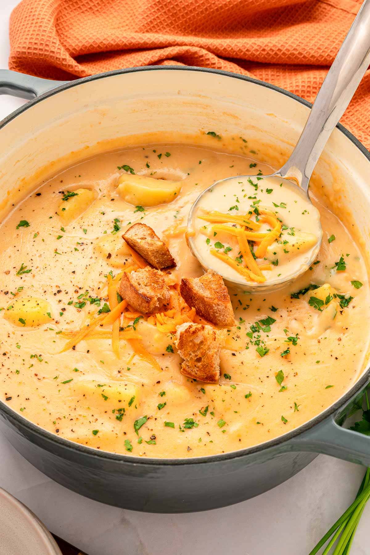 Cheesy Potato Soup in pot with croutons and ladle.