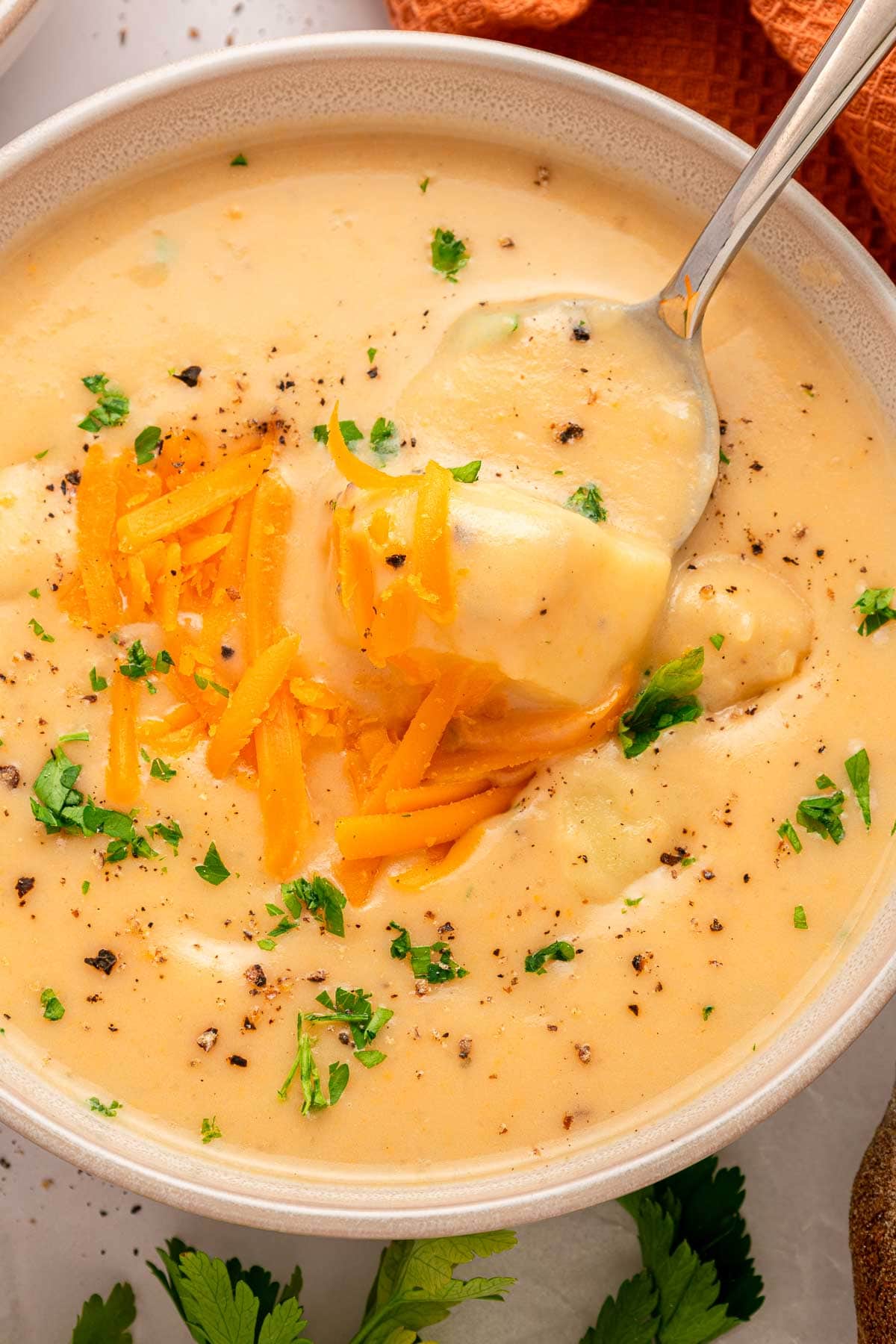 Cheesy Potato Soup aerial view in bowl with spoon.