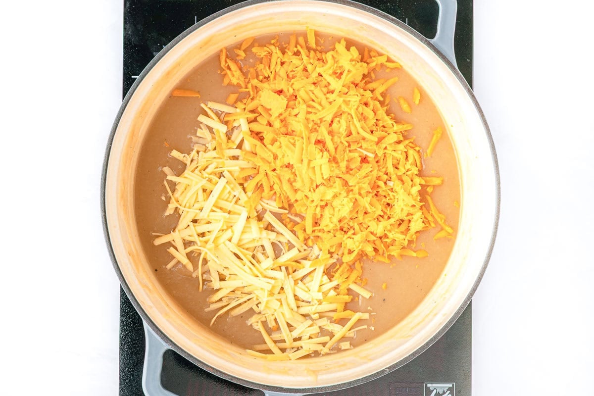 Adding shredded cheese to Cheesy Potato Soup.