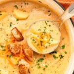 Cheesy Potato Soup aerial view with ladle and garnishes.