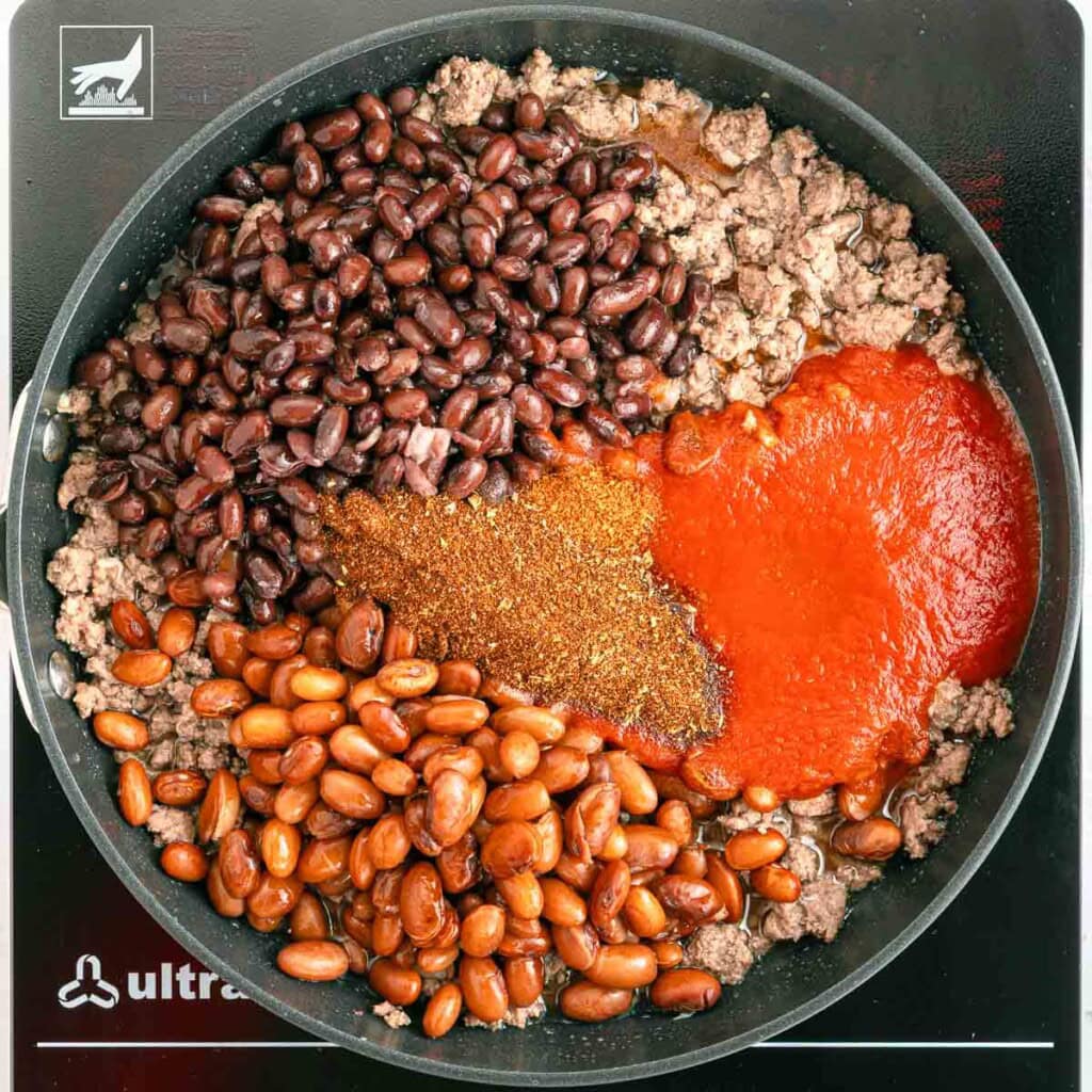 Adding beans, tomato sauce, and chili seasonong to pan.
