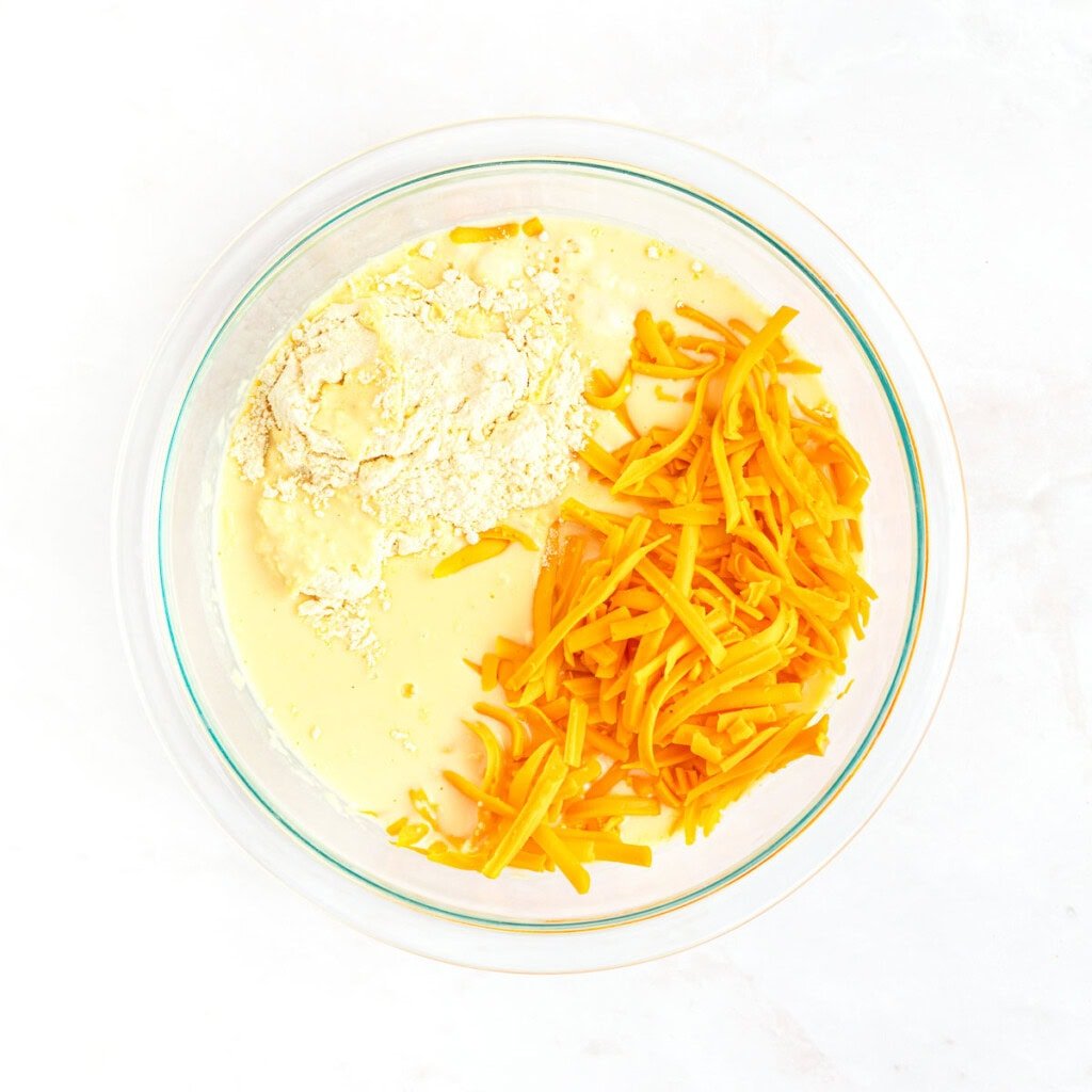 Adding cornbread mix and shredded cheese for cornbread batter.