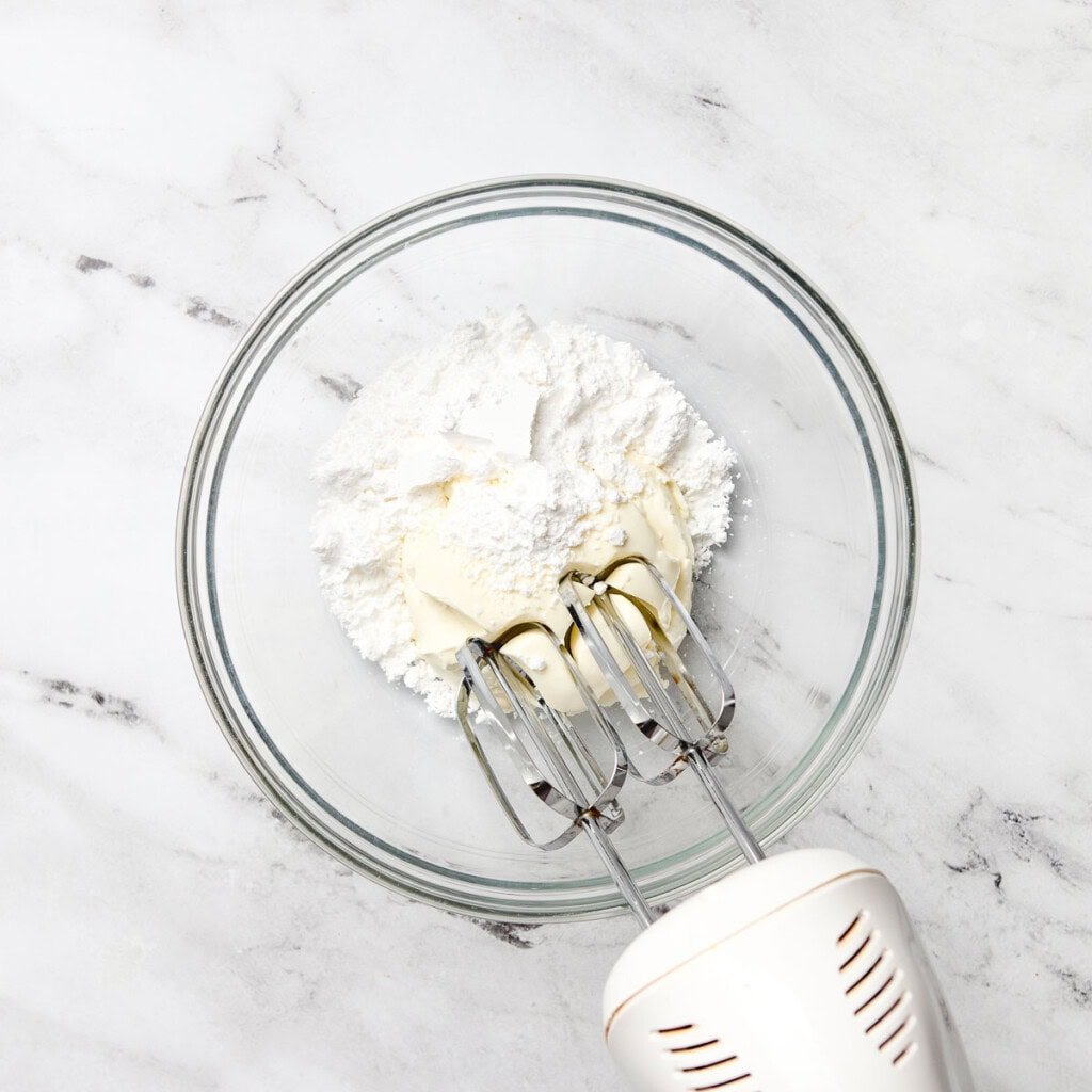 Cream cheese and powdered sugar in bowl.