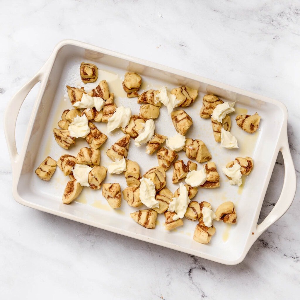 Adding cream cheese dollops to baking dish.