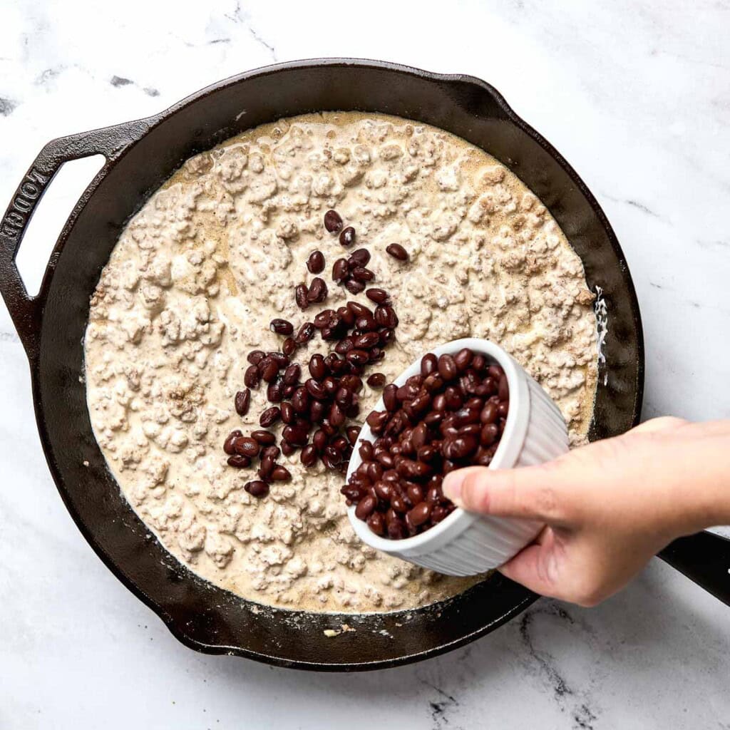 Adding black beans to cowboy tater tot casserole.