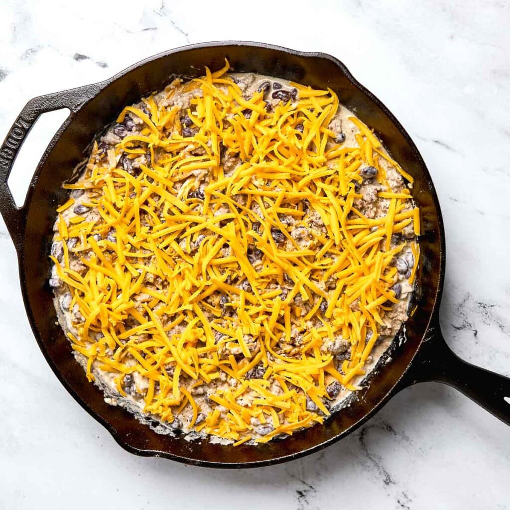 Cheese sprinkled on top of Cowboy Casserole.